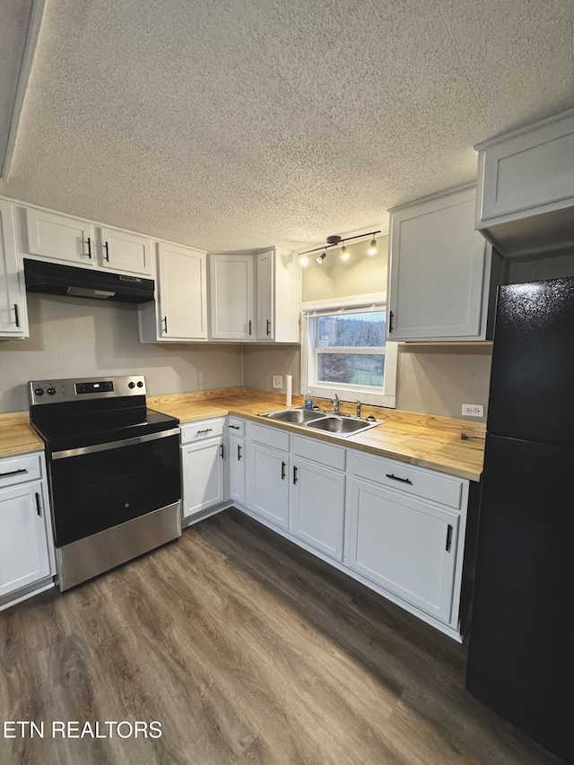 kitchen with wooden counters, black refrigerator, sink, stainless steel electric range oven, and white cabinetry