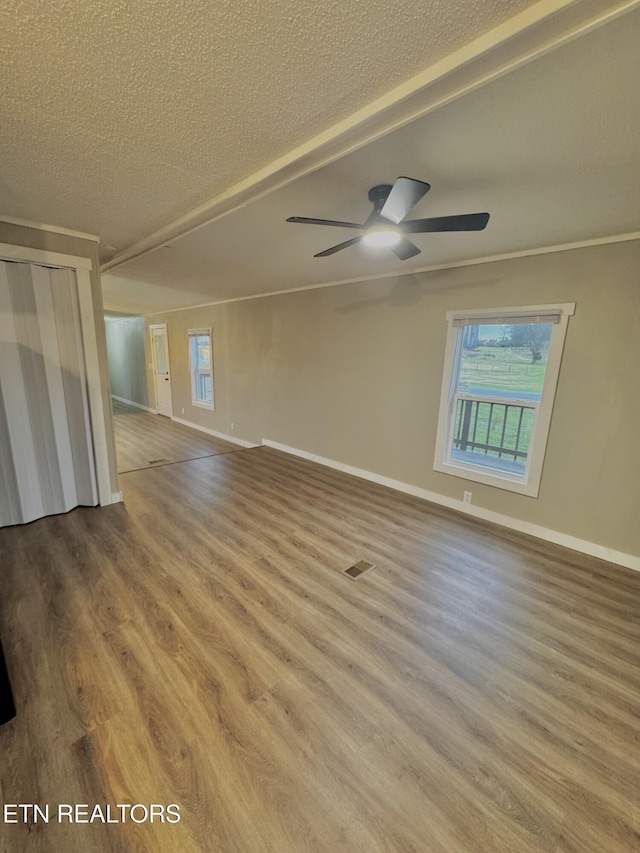 empty room featuring ceiling fan, crown molding, wood-type flooring, and a textured ceiling