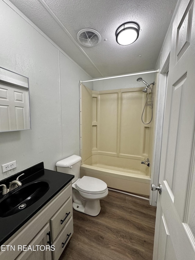 full bathroom featuring vanity, a textured ceiling, wood-type flooring, shower / bathing tub combination, and toilet