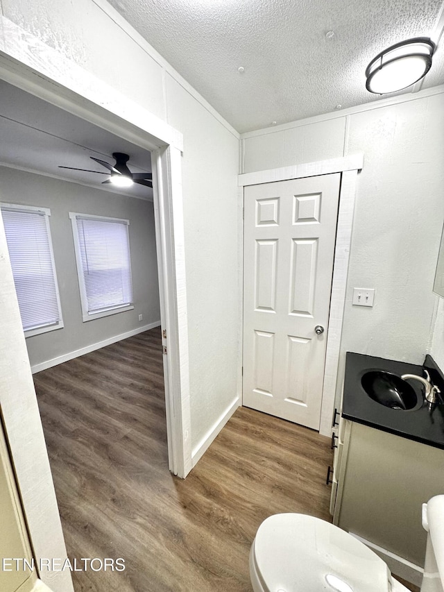 bathroom featuring a textured ceiling, vanity, ceiling fan, hardwood / wood-style flooring, and toilet