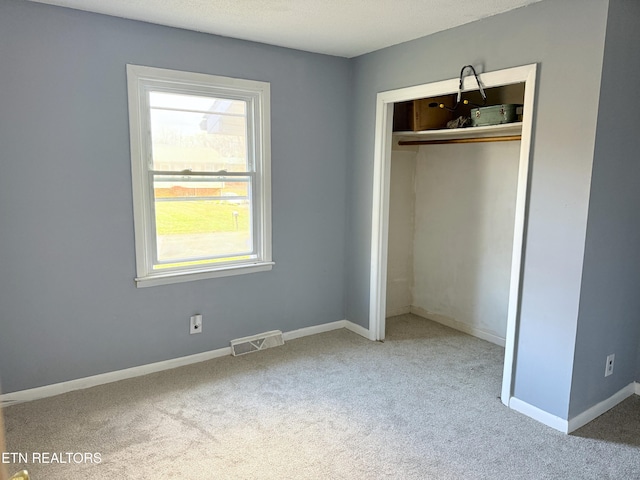 unfurnished bedroom featuring carpet, a textured ceiling, and a closet