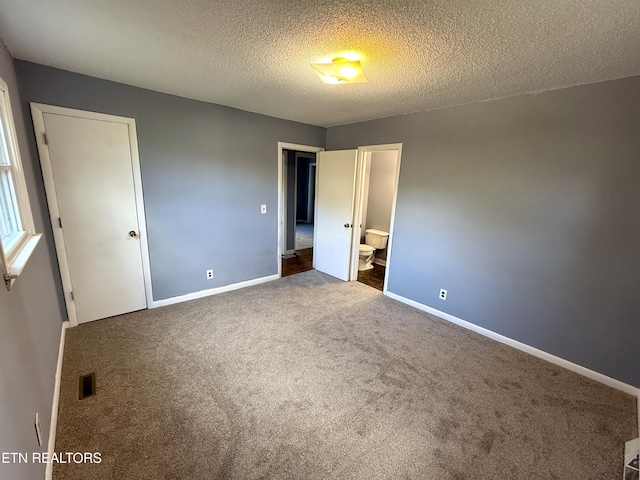 unfurnished bedroom with carpet floors, a textured ceiling, and connected bathroom