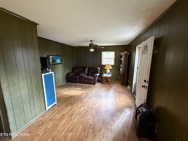 living room featuring wooden walls, ceiling fan, and light hardwood / wood-style floors