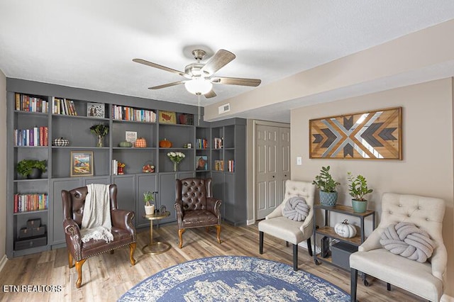 living area featuring hardwood / wood-style floors and ceiling fan