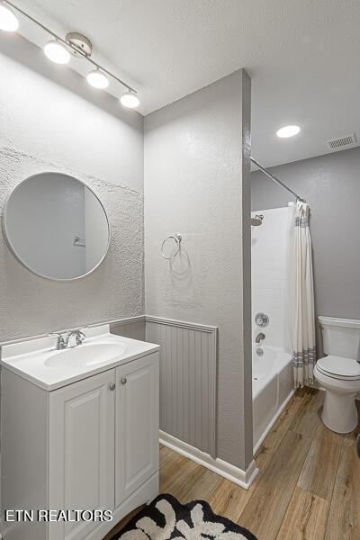 full bathroom with wood-type flooring, vanity, shower / tub combo, and toilet