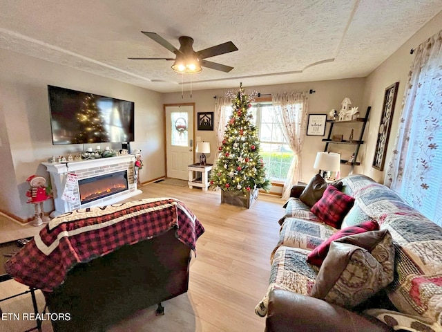 living room featuring ceiling fan, light hardwood / wood-style floors, and a textured ceiling