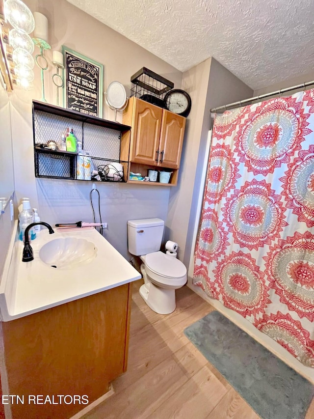 bathroom with vanity, a textured ceiling, hardwood / wood-style flooring, toilet, and curtained shower