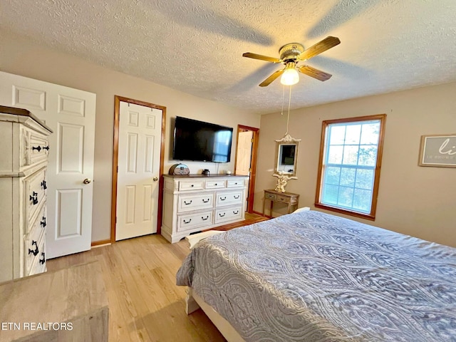 bedroom with a textured ceiling, light wood-type flooring, and ceiling fan