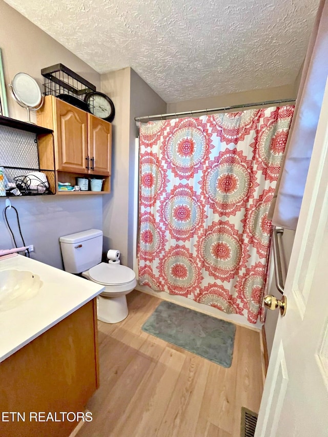 full bathroom featuring vanity, shower / bath combo, hardwood / wood-style flooring, toilet, and a textured ceiling