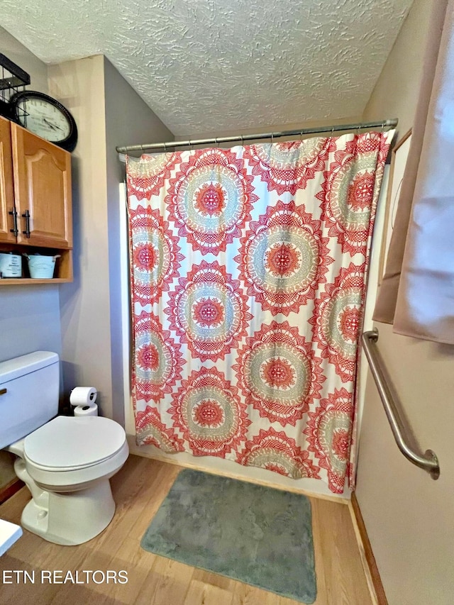 bathroom with toilet, shower / bathtub combination with curtain, a textured ceiling, and hardwood / wood-style flooring