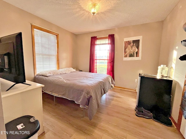 bedroom with light hardwood / wood-style floors and a textured ceiling