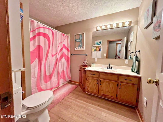 bathroom with hardwood / wood-style floors, vanity, toilet, a textured ceiling, and walk in shower