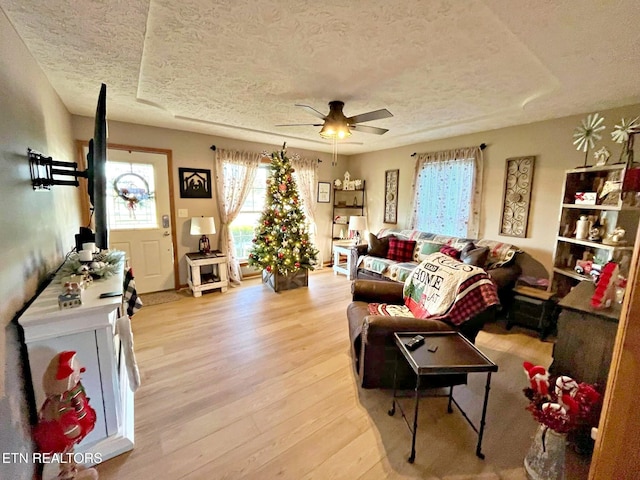 living room featuring a textured ceiling, light wood-type flooring, and ceiling fan