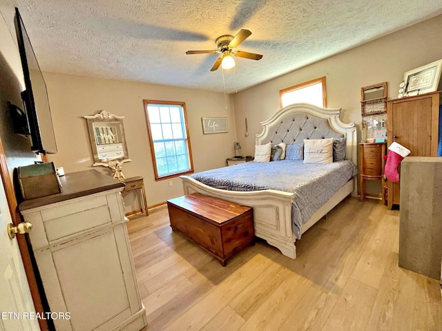 bedroom with ceiling fan, light hardwood / wood-style floors, and a textured ceiling