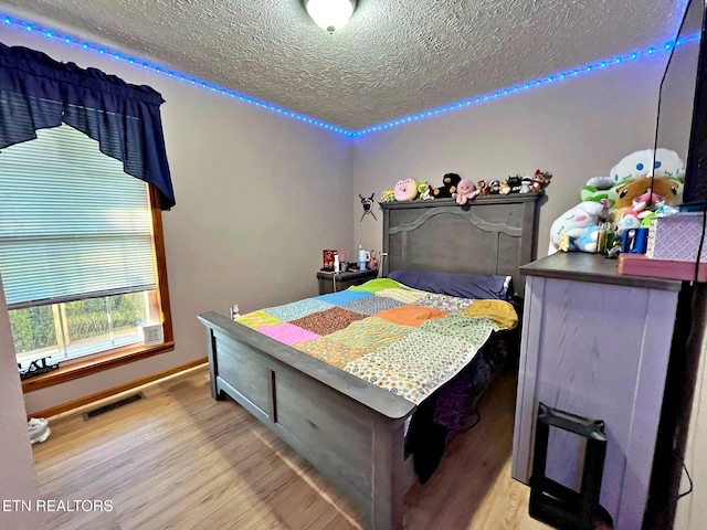 bedroom with light wood-type flooring and a textured ceiling