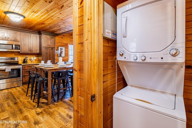 laundry room featuring wood walls, wooden ceiling, stacked washer / drying machine, and hardwood / wood-style flooring