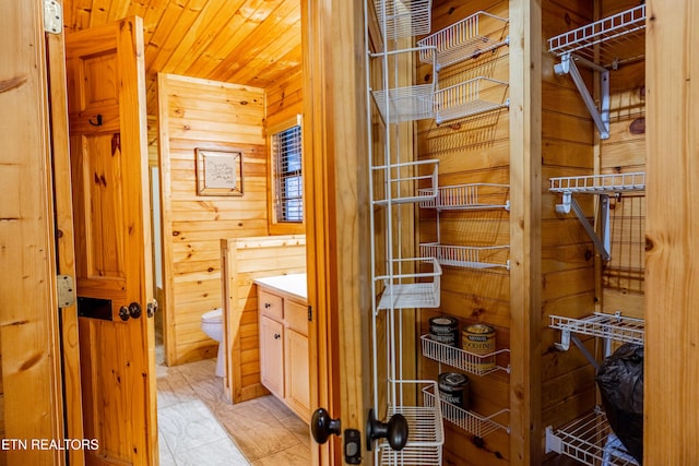 bathroom with vanity, wood walls, toilet, and wooden ceiling