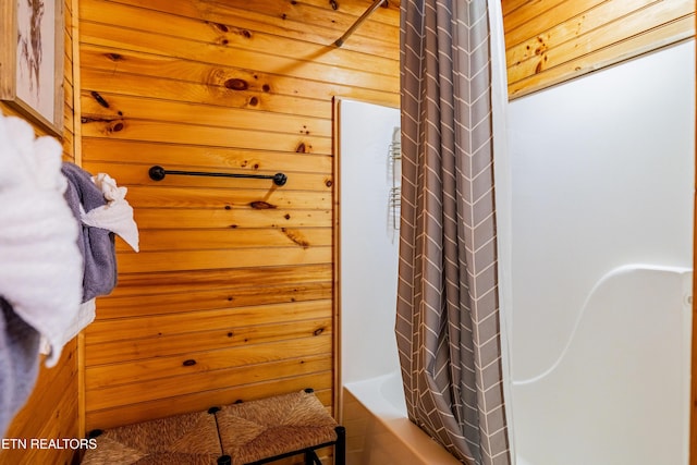 bathroom with wooden walls and shower / bathtub combination with curtain