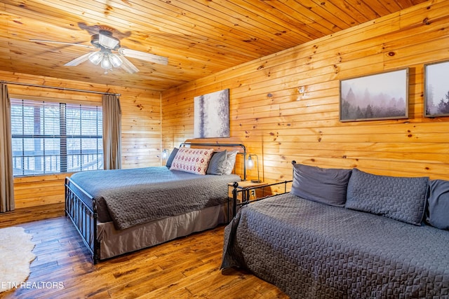 bedroom with ceiling fan, hardwood / wood-style floors, wooden ceiling, and wood walls