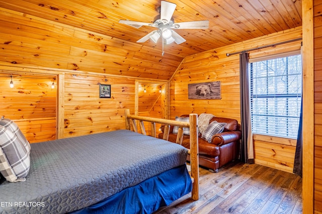 bedroom with wood-type flooring, lofted ceiling, and wood walls