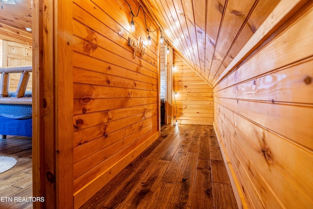 hall with wood ceiling, wooden walls, wood-type flooring, and vaulted ceiling