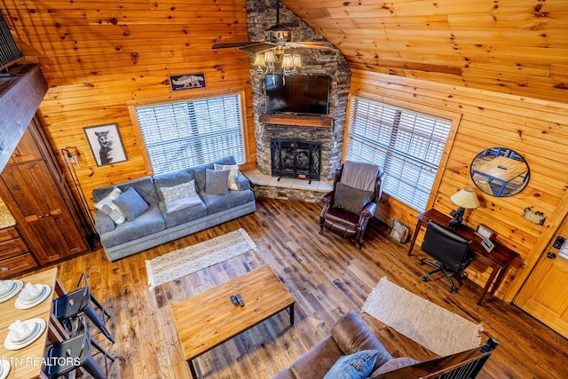 living room featuring plenty of natural light, ceiling fan, wood-type flooring, and wooden walls