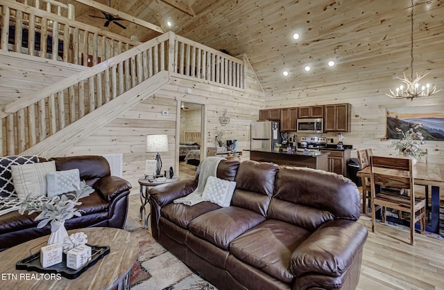 living room with an inviting chandelier, wood ceiling, wood walls, and high vaulted ceiling