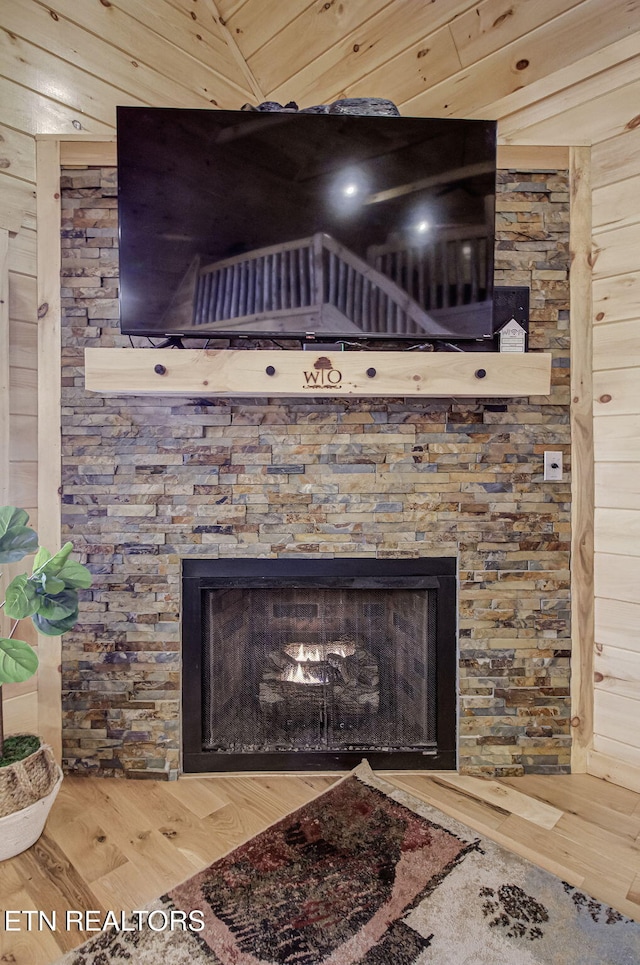 room details featuring wooden walls, hardwood / wood-style flooring, and a stone fireplace