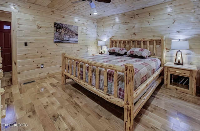 bedroom with light wood-type flooring, ceiling fan, wood ceiling, and wooden walls