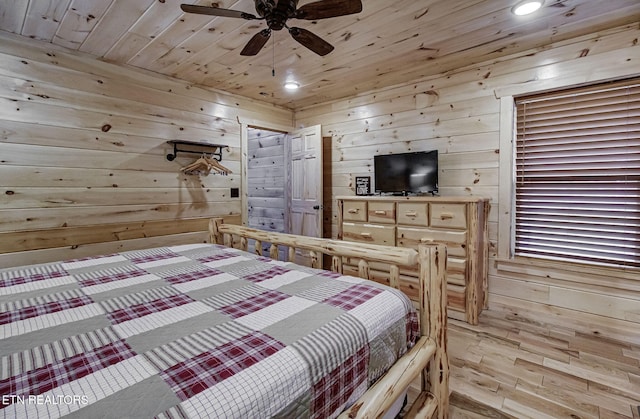 bedroom with ceiling fan, wood walls, and wooden ceiling