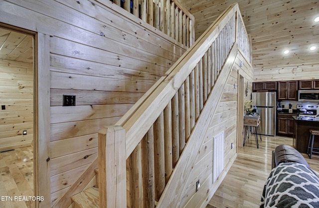 stairs featuring hardwood / wood-style flooring and wood walls