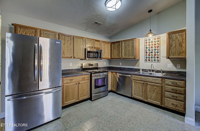 kitchen with sink, a textured ceiling, decorative light fixtures, lofted ceiling, and appliances with stainless steel finishes