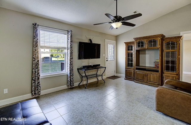 tiled living room featuring ceiling fan, a healthy amount of sunlight, a textured ceiling, and vaulted ceiling