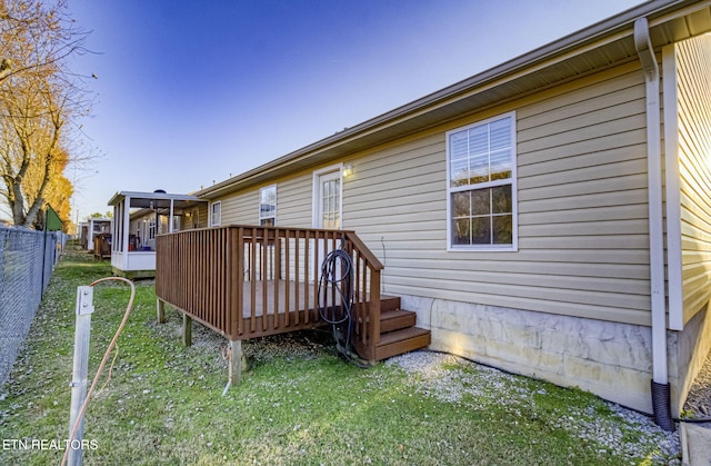 wooden deck featuring a sunroom and a lawn