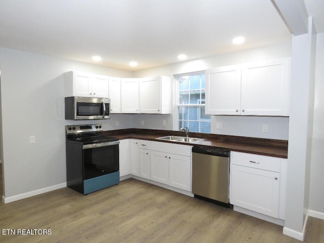 kitchen with white cabinetry, sink, light hardwood / wood-style floors, and appliances with stainless steel finishes