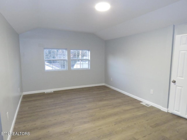 empty room featuring hardwood / wood-style flooring and vaulted ceiling