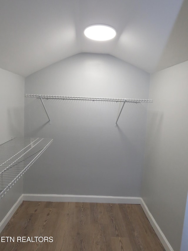 walk in closet with dark hardwood / wood-style flooring and lofted ceiling