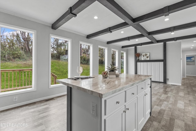 kitchen with white cabinets, plenty of natural light, a kitchen island, and light stone counters