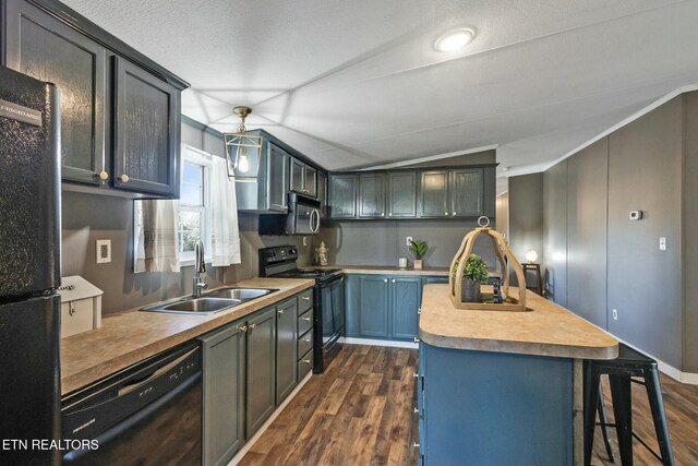 kitchen with black appliances, sink, hanging light fixtures, vaulted ceiling, and dark hardwood / wood-style flooring