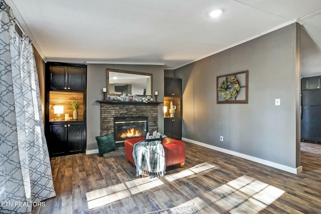 living room featuring a stone fireplace, crown molding, and dark hardwood / wood-style flooring