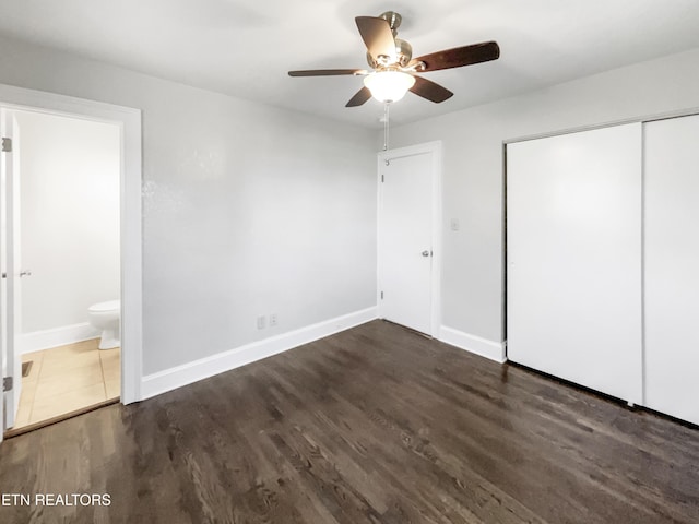 unfurnished bedroom with connected bathroom, dark hardwood / wood-style flooring, a closet, and ceiling fan