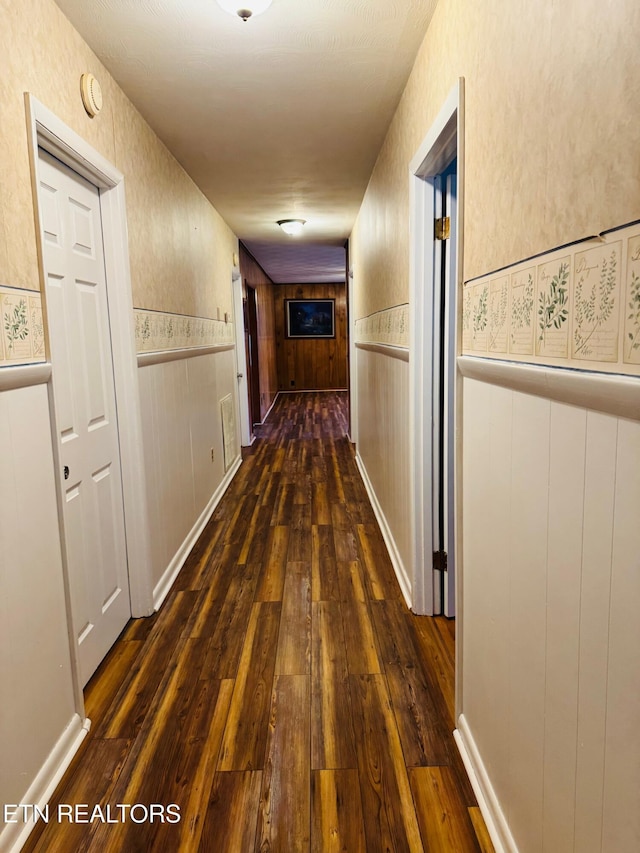 hall with dark wood-type flooring and wood walls