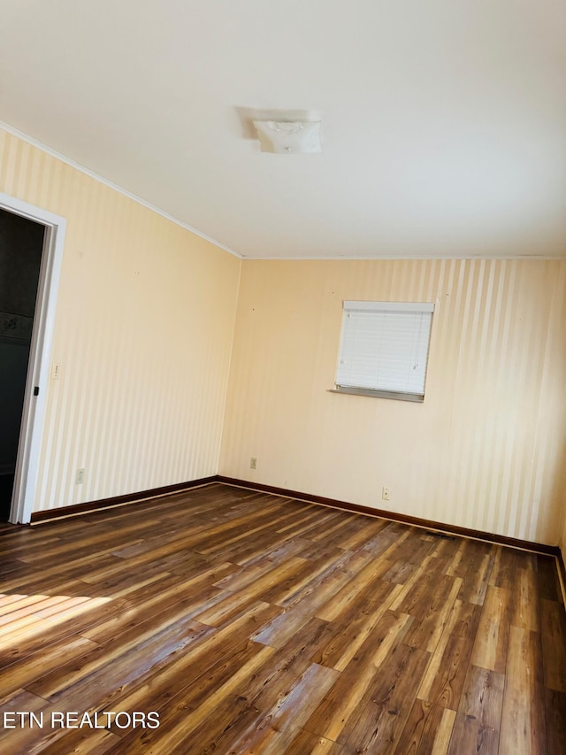 empty room with vaulted ceiling, crown molding, and dark hardwood / wood-style floors