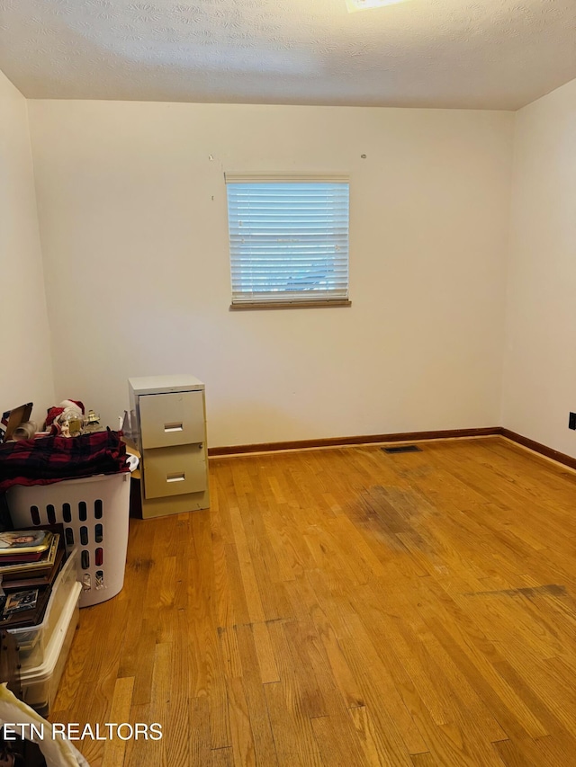 unfurnished room with a textured ceiling and light wood-type flooring