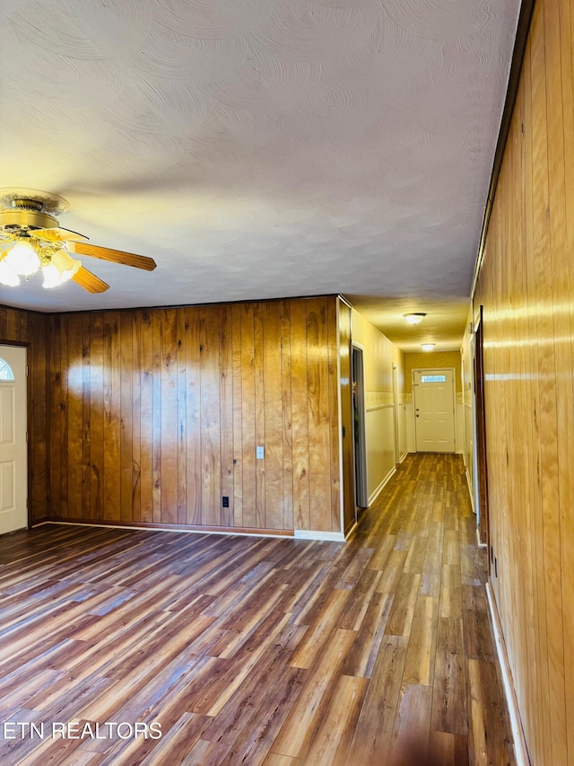 spare room featuring wood-type flooring, a textured ceiling, ceiling fan, and wooden walls