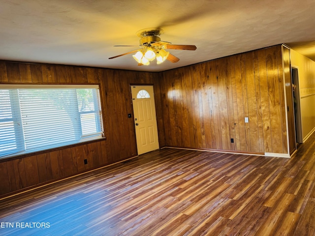 entryway featuring wood walls, ceiling fan, and dark wood-type flooring