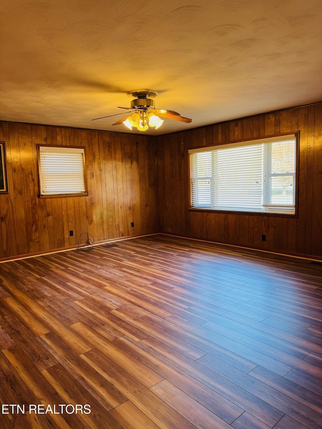 spare room featuring hardwood / wood-style floors, ceiling fan, and wood walls