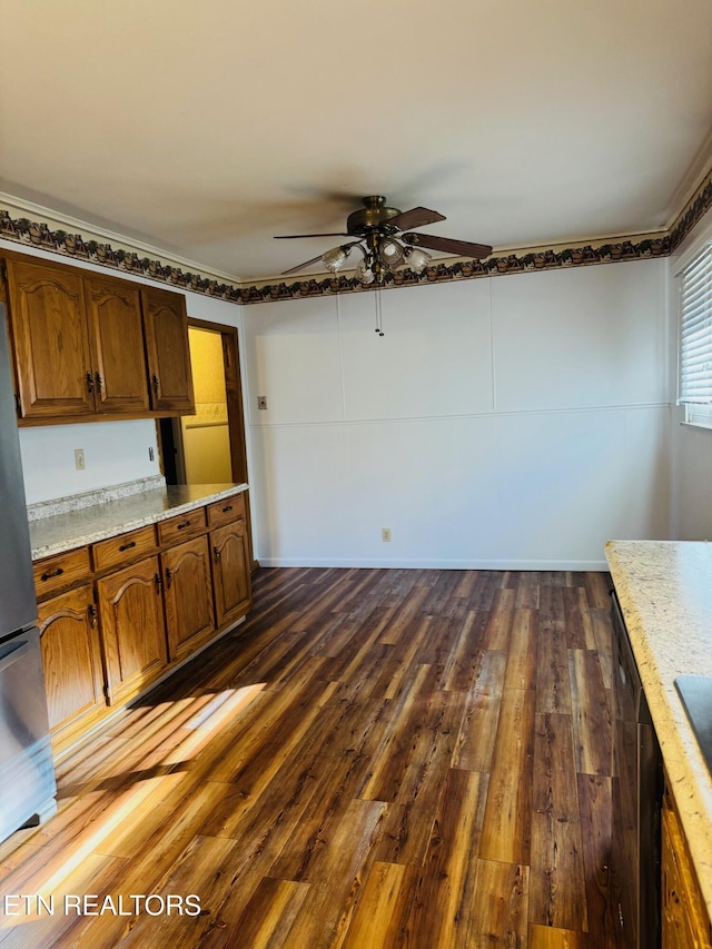 115 Greasy Cove Rd, Cosby, TN 37722 - kitchen with dark wood-style floors, freestanding refrigerator, ceiling fan, brown cabinets, and light stone countertops