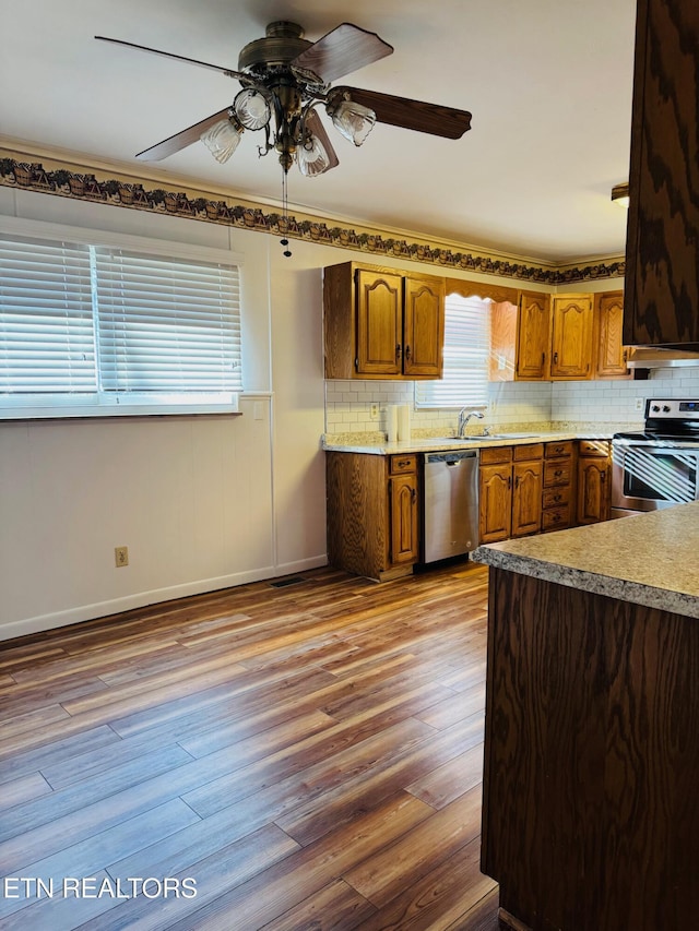 kitchen with tasteful backsplash, ceiling fan, light wood-type flooring, and appliances with stainless steel finishes