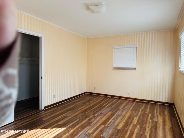 empty room with dark hardwood / wood-style floors and crown molding